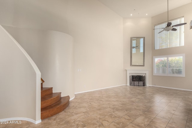 unfurnished living room featuring a high ceiling and ceiling fan