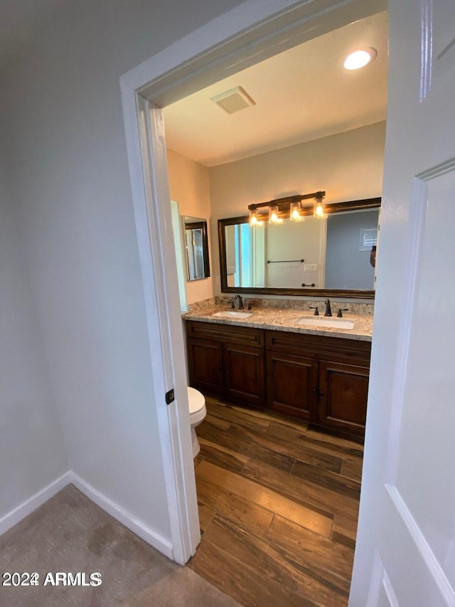 bathroom with wood-type flooring, vanity, and toilet