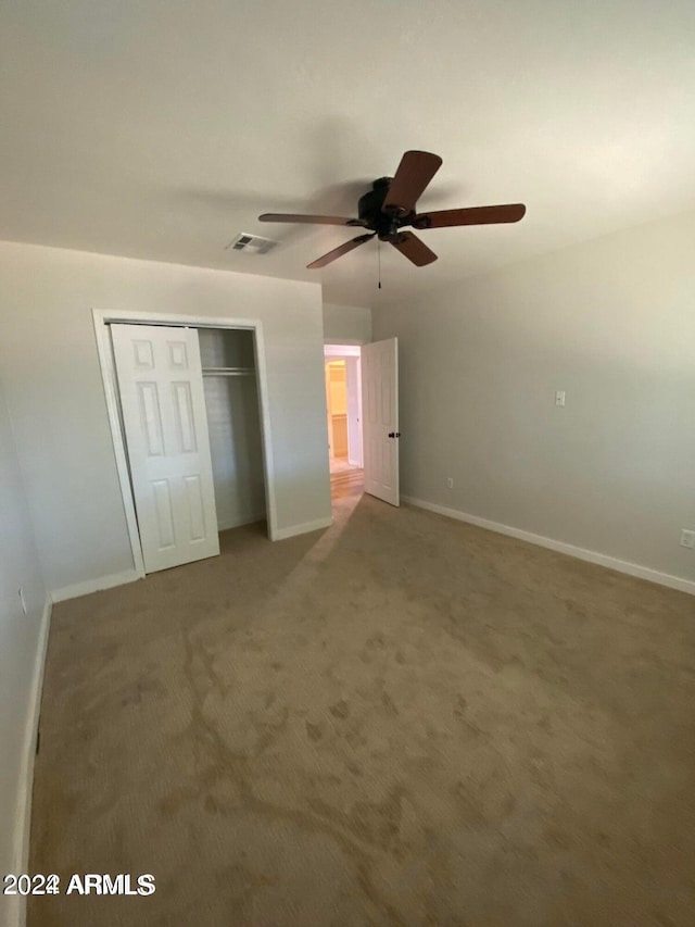 unfurnished bedroom with carpet flooring, ceiling fan, and a closet