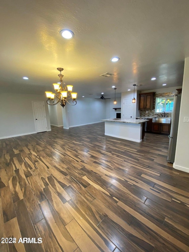 unfurnished living room with a chandelier, dark hardwood / wood-style floors, and sink