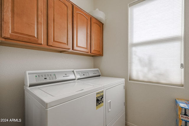 washroom with cabinets, plenty of natural light, and washer and clothes dryer