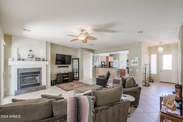 living room featuring ceiling fan, light tile patterned flooring, and a tiled fireplace