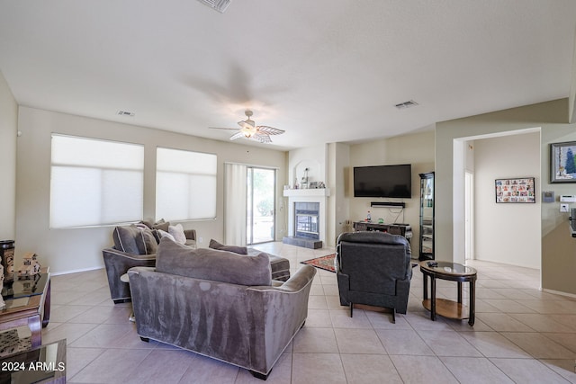 living room with a tile fireplace, light tile patterned flooring, and ceiling fan