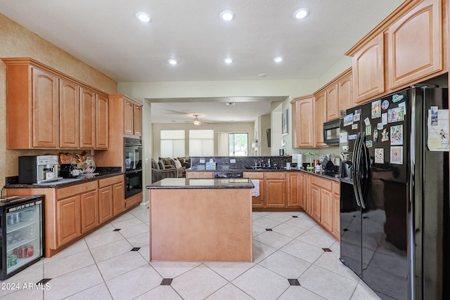 kitchen with light tile patterned flooring, black appliances, a center island, beverage cooler, and sink