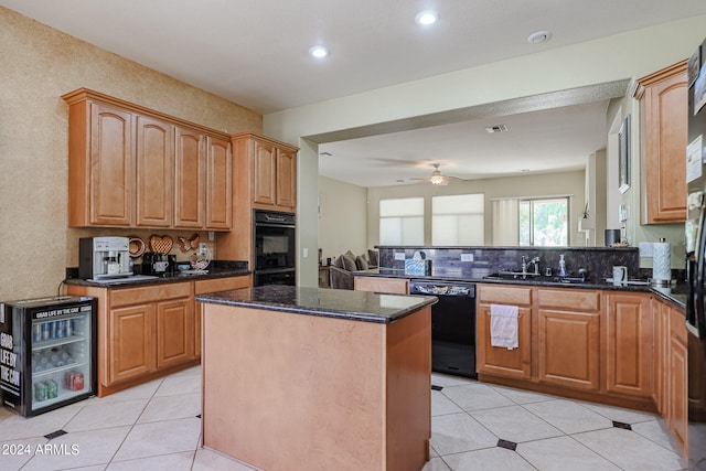 kitchen featuring dark stone countertops, black appliances, a center island, ceiling fan, and sink