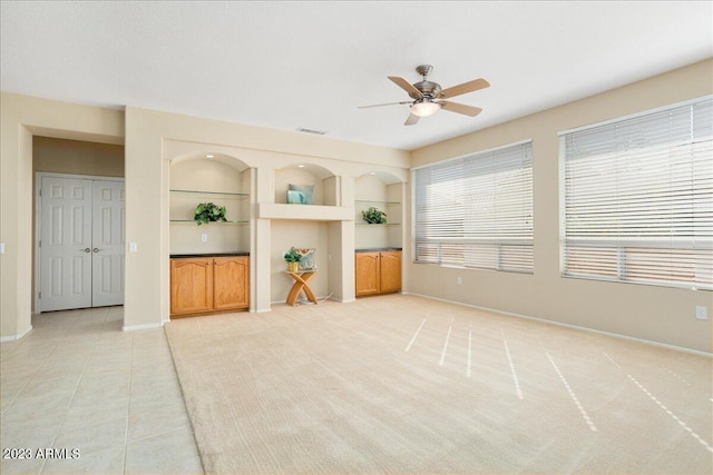 unfurnished living room featuring ceiling fan, built in features, and light tile patterned floors