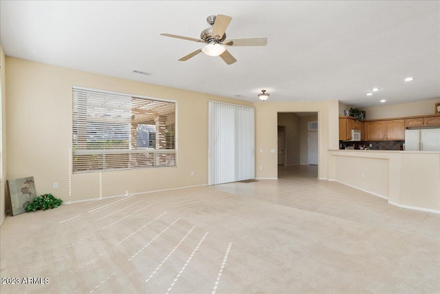 unfurnished living room with light colored carpet and ceiling fan