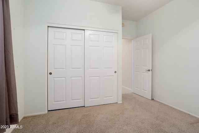 unfurnished bedroom featuring a closet and light colored carpet