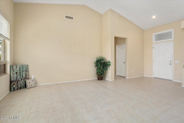 tiled empty room featuring high vaulted ceiling