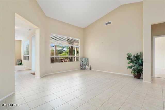 tiled empty room featuring high vaulted ceiling