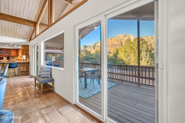 doorway featuring a mountain view, lofted ceiling with beams, and wooden ceiling