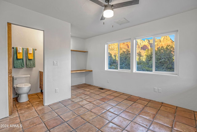 unfurnished bedroom with connected bathroom, ceiling fan, and light tile patterned floors