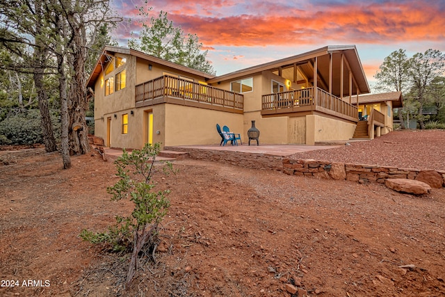 back house at dusk featuring a balcony and a patio