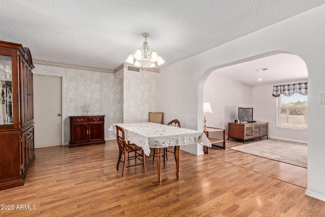 922 S 80th St, Mesa, AZ 85208 - dining room featuring arched walkways, light wood-type flooring, a chandelier, a textured ceiling, and baseboards