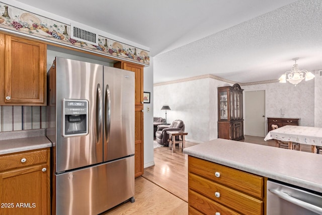922 S 80th St, Mesa, AZ 85208 - kitchen with stainless steel appliances, a chandelier, light wood finished floors, brown cabinetry, and wallpapered walls