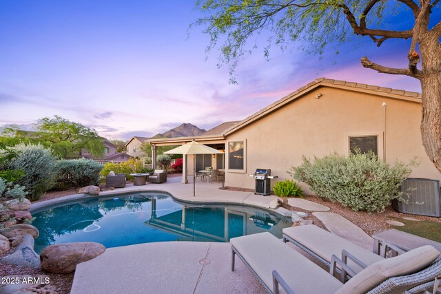 10623 E Acacia Dr, Scottsdale, AZ 85255 - pool at dusk featuring central AC unit, grilling area, a patio area, and a fenced in pool