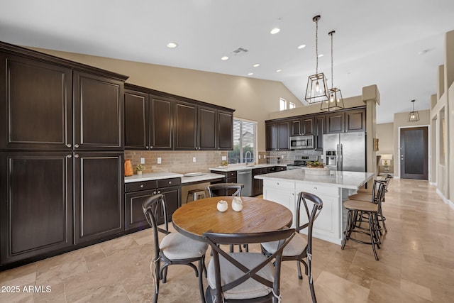 10623 E Acacia Dr, Scottsdale, AZ 85255 - kitchen with stainless steel appliances, vaulted ceiling, dark brown cabinetry, decorative backsplash, and a kitchen island
