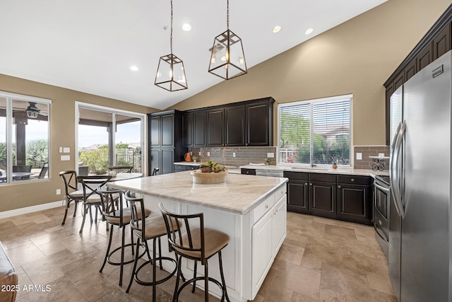 10623 E Acacia Dr, Scottsdale, AZ 85255 - kitchen featuring freestanding refrigerator, a center island, stone tile flooring, vaulted ceiling, and backsplash