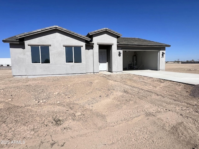 ranch-style house featuring driveway, an attached garage, a tile roof, and stucco siding