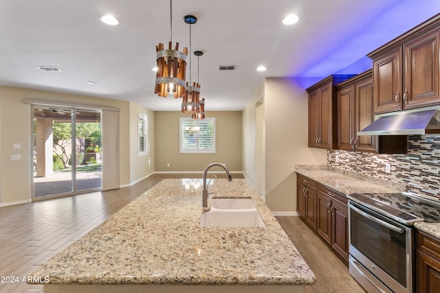 kitchen with a center island with sink, sink, stainless steel electric stove, and backsplash