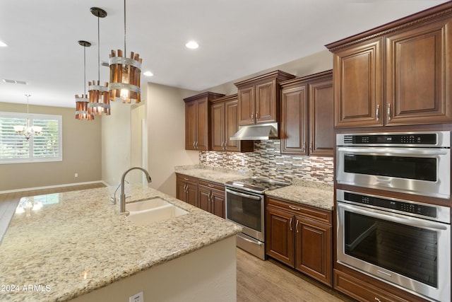 kitchen featuring light hardwood / wood-style flooring, appliances with stainless steel finishes, sink, and hanging light fixtures