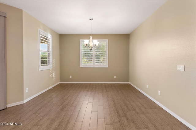 empty room with hardwood / wood-style flooring and a chandelier