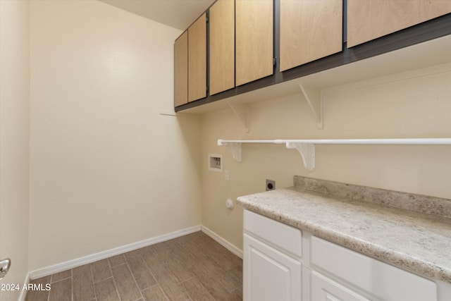 clothes washing area with electric dryer hookup, washer hookup, light hardwood / wood-style floors, and cabinets