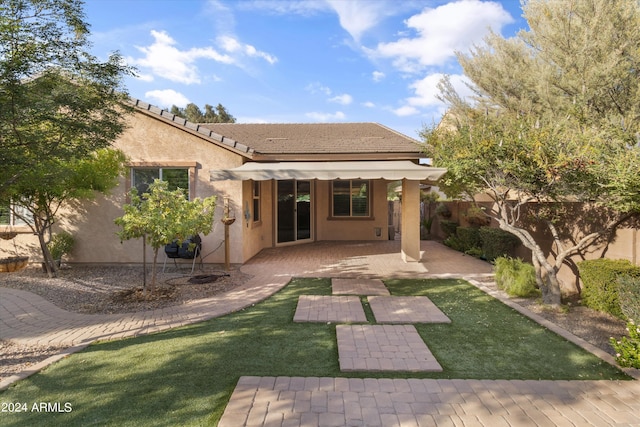 rear view of house featuring a patio area and a lawn