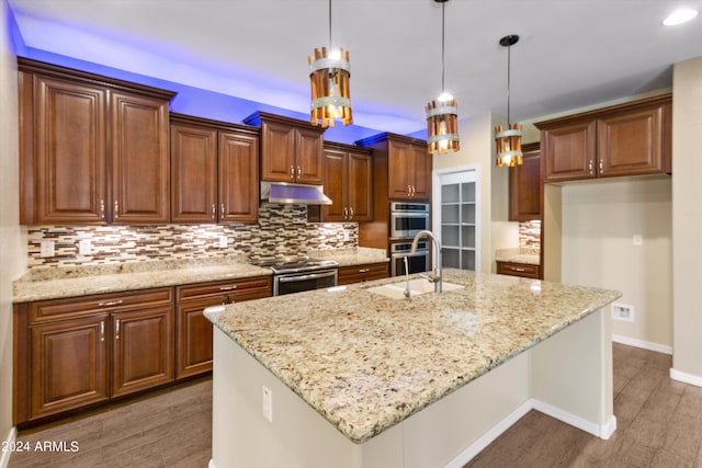 kitchen with appliances with stainless steel finishes, dark hardwood / wood-style floors, a kitchen island with sink, and hanging light fixtures