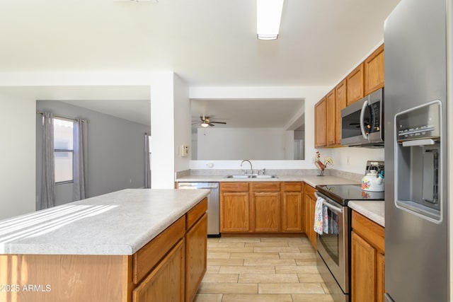 kitchen with stainless steel appliances, a kitchen island, ceiling fan, and sink