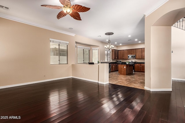 unfurnished living room featuring dark wood-style floors, visible vents, ornamental molding, baseboards, and ceiling fan with notable chandelier