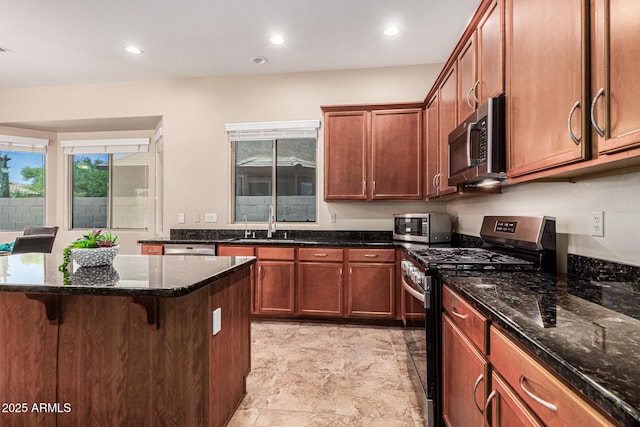 kitchen with a breakfast bar, stainless steel appliances, recessed lighting, a sink, and dark stone counters