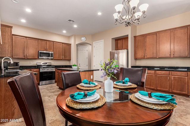 kitchen featuring visible vents, brown cabinetry, arched walkways, appliances with stainless steel finishes, and a sink