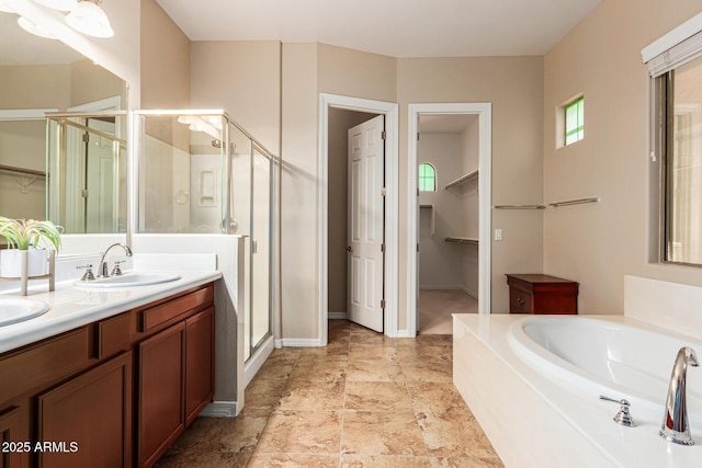 full bath featuring a garden tub, a sink, double vanity, a stall shower, and a walk in closet