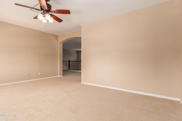 unfurnished room featuring arched walkways, light colored carpet, ceiling fan, and baseboards