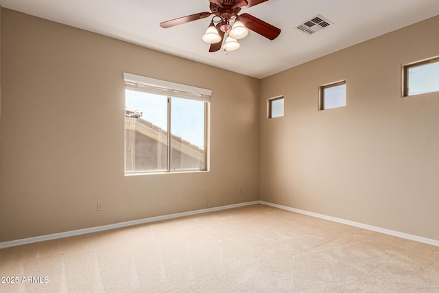 empty room featuring a ceiling fan, visible vents, light carpet, and baseboards