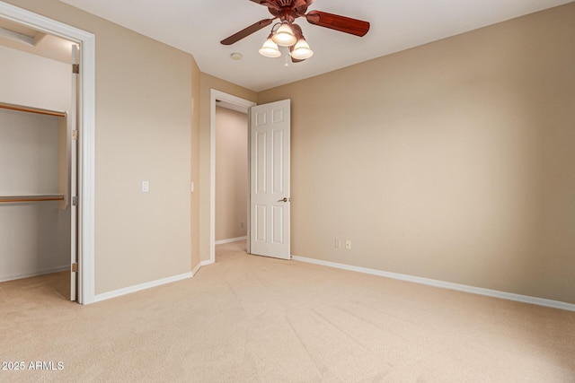 unfurnished bedroom featuring a walk in closet, a closet, carpet flooring, and baseboards