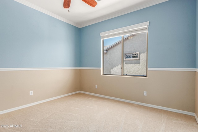 empty room with ornamental molding, carpet flooring, baseboards, and a ceiling fan