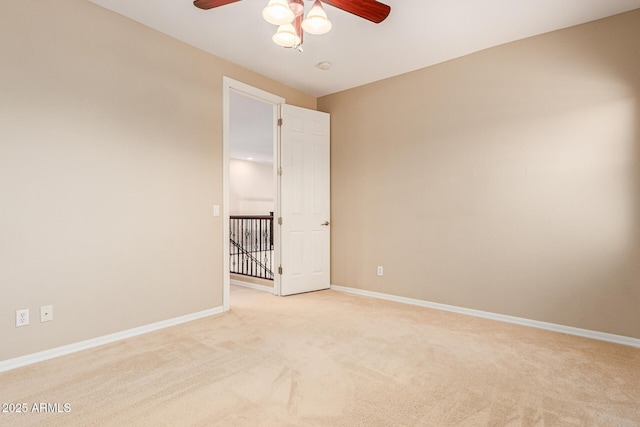 empty room with a ceiling fan, light carpet, and baseboards