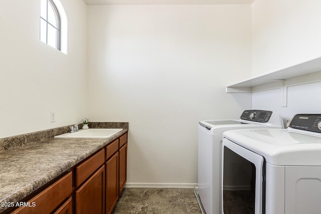 laundry area featuring washing machine and clothes dryer, a sink, and baseboards