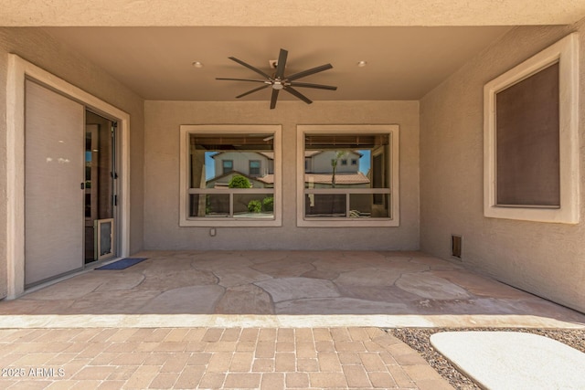 view of exterior entry featuring ceiling fan, a patio area, and stucco siding