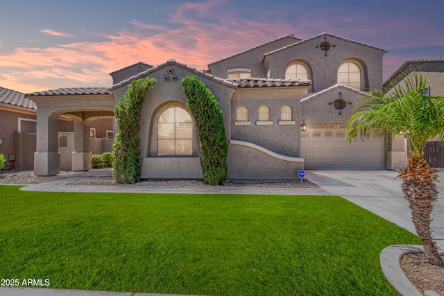 mediterranean / spanish-style house with stucco siding, a lawn, a garage, driveway, and a tiled roof