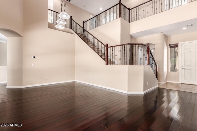 interior space featuring arched walkways, visible vents, baseboards, stairway, and hardwood / wood-style floors