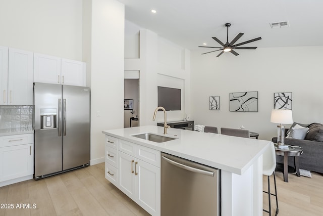 kitchen featuring a breakfast bar, sink, white cabinetry, stainless steel appliances, and a kitchen island with sink