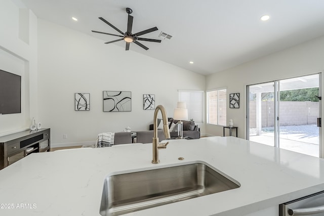 kitchen featuring vaulted ceiling, light stone countertops, sink, and ceiling fan