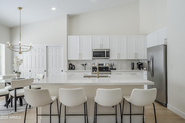 kitchen featuring pendant lighting, stainless steel appliances, backsplash, and white cabinets