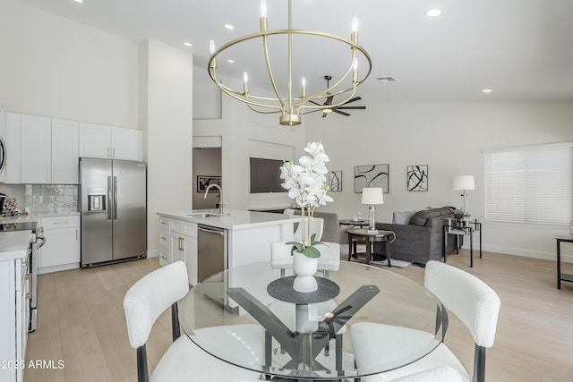 dining room with an inviting chandelier, sink, a high ceiling, and light wood-type flooring