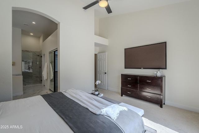 carpeted bedroom with ceiling fan, a towering ceiling, and ensuite bath