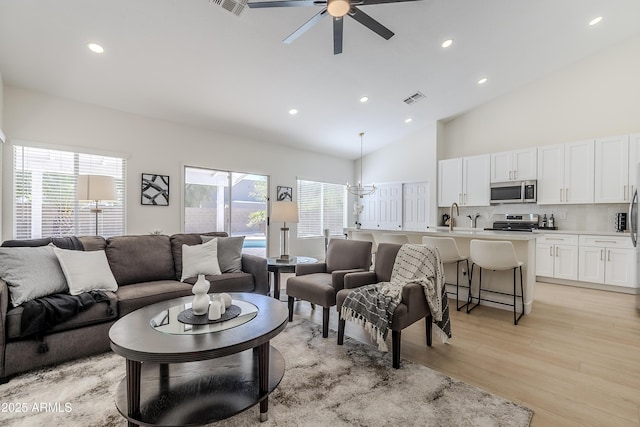 living room featuring ceiling fan, high vaulted ceiling, light hardwood / wood-style flooring, and a wealth of natural light