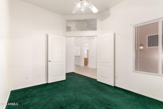 unfurnished bedroom featuring baseboards, a ceiling fan, and dark carpet